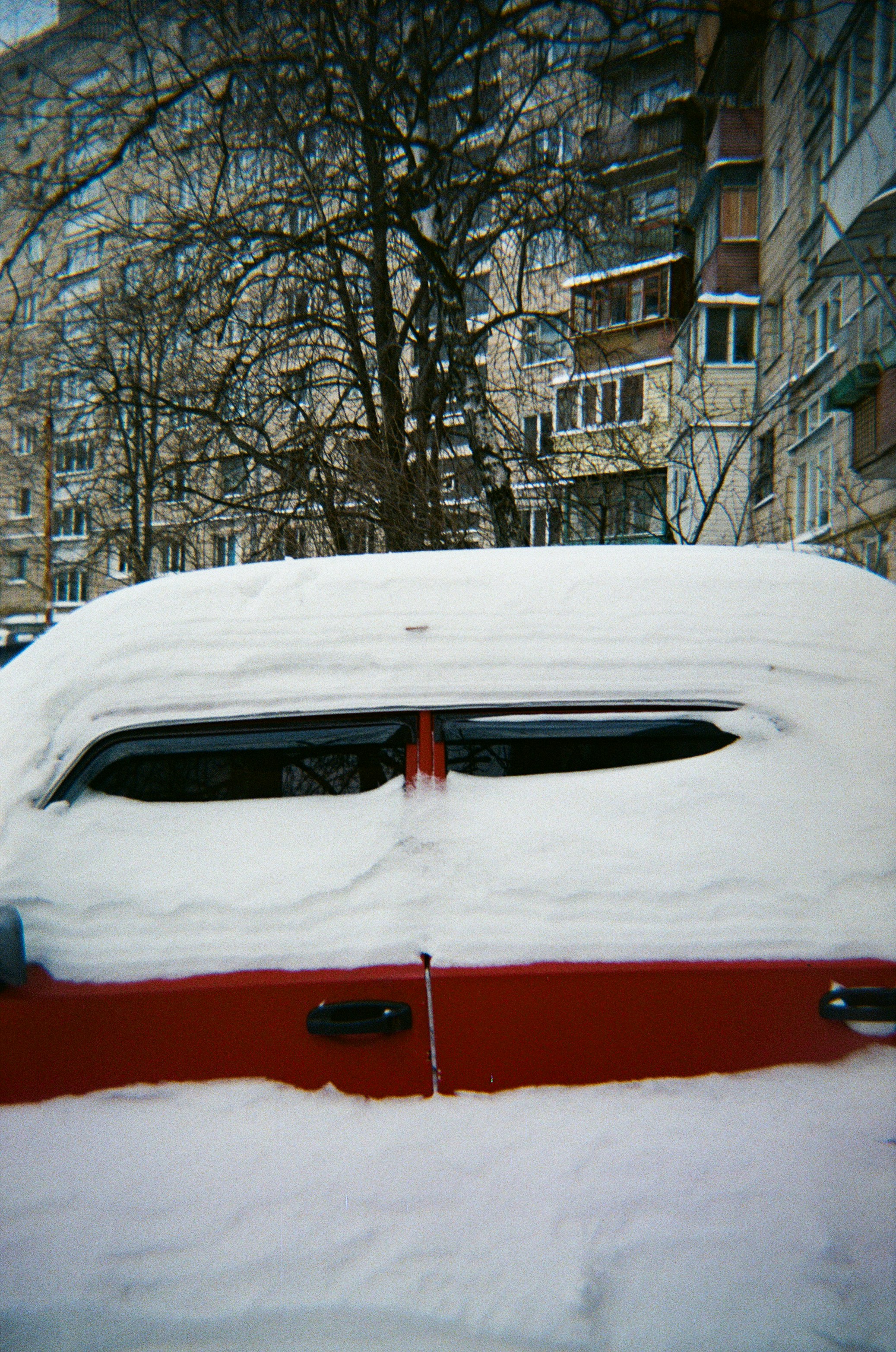 a car covered in snow in front of a building