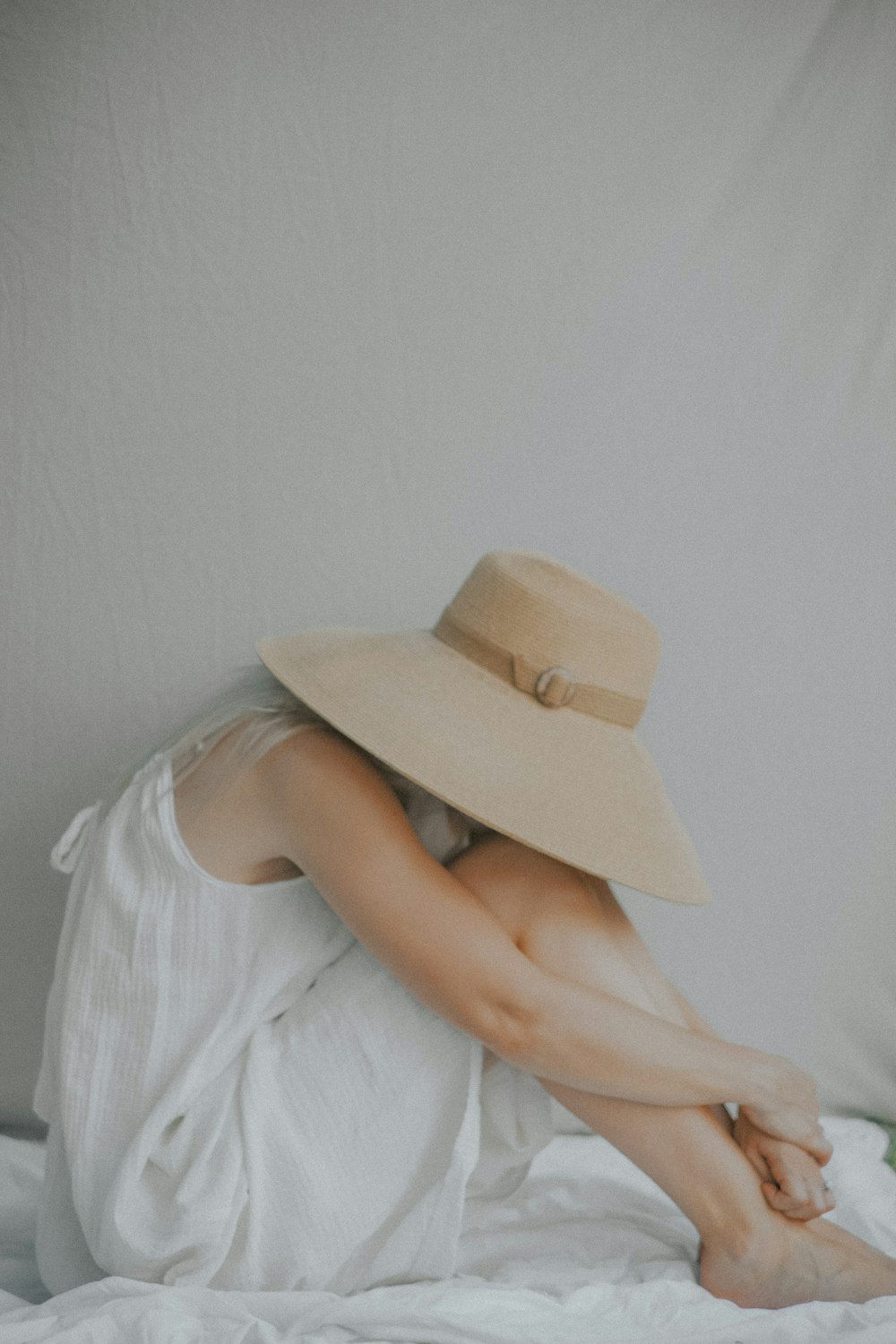 a woman laying on a bed wearing a hat