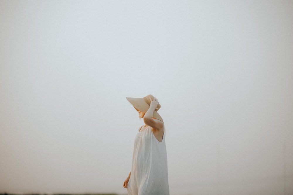 a woman wearing a white dress and a hat