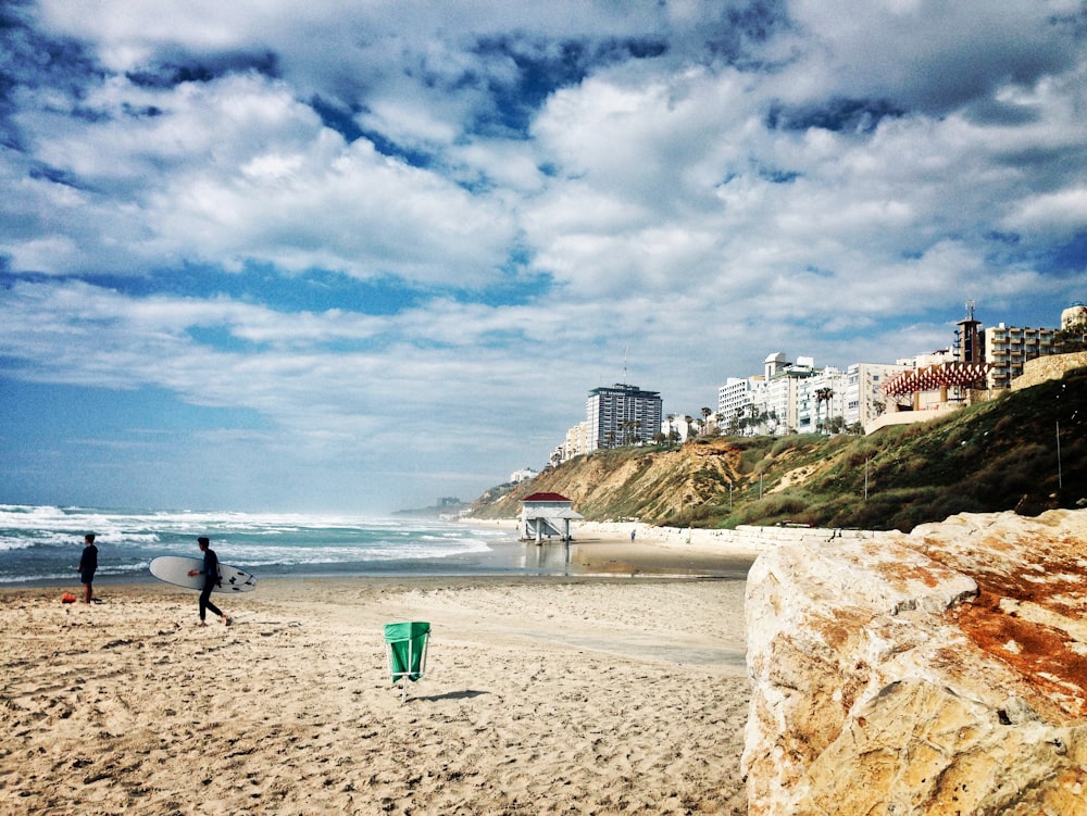 a couple of people walking on a beach next to the ocean