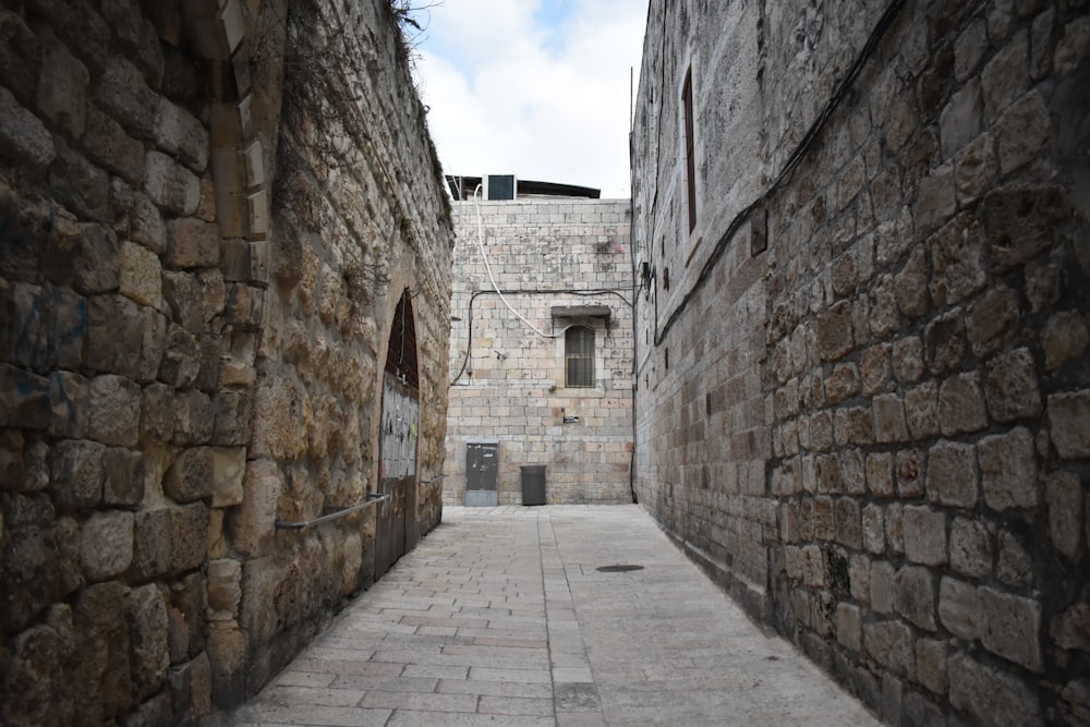 a narrow alley way with a stone building in the background