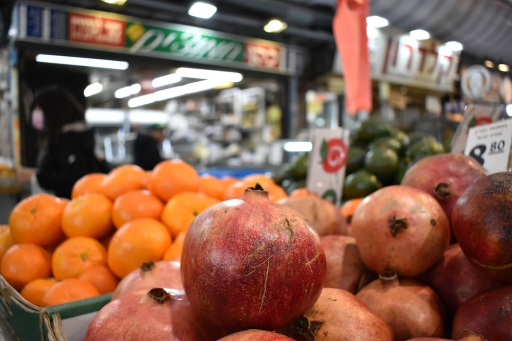 Ein Haufen Granatäpfel sitzt auf einem Orangenhaufen