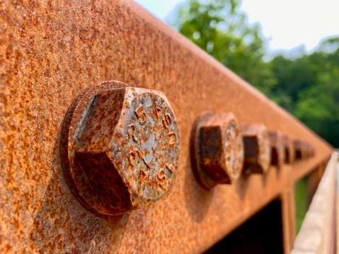 a rusted metal wall with three knobs on it