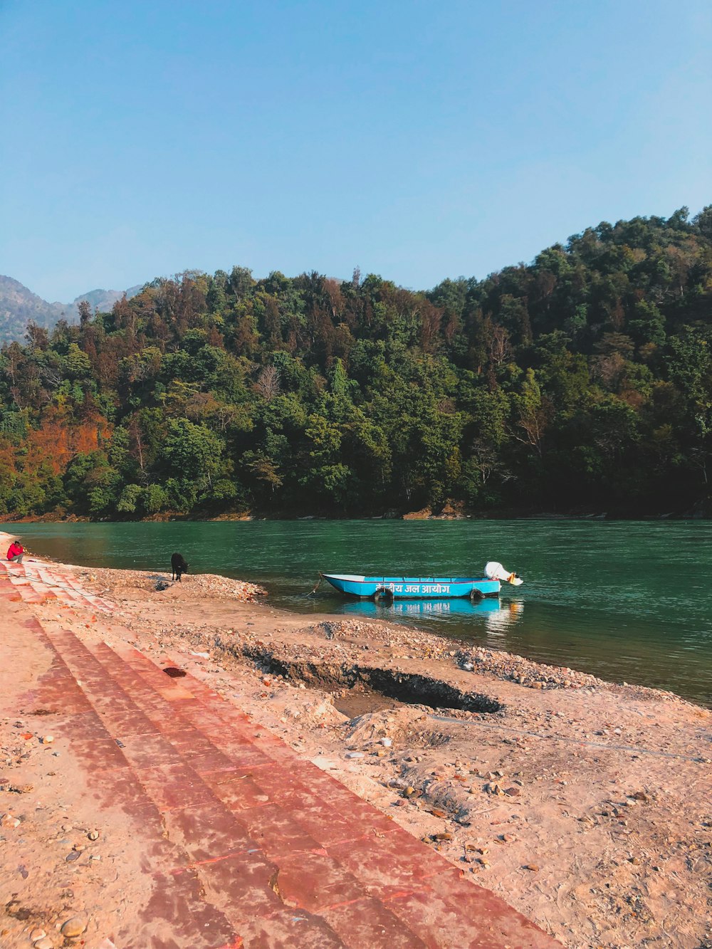 a blue boat sitting on the shore of a lake