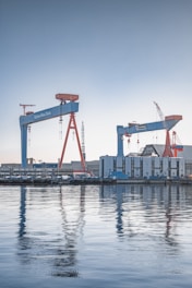 a large body of water with cranes in the background