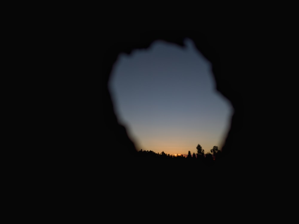 a view of a sunset through a hole in a wall