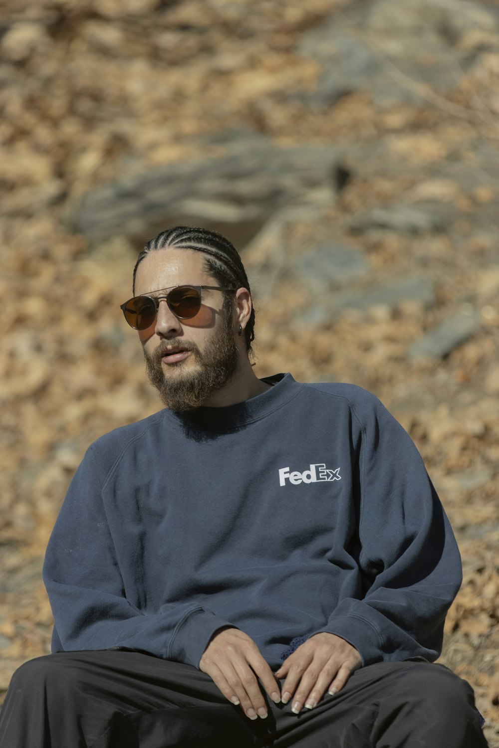 a man wearing a fedex sweatshirt sitting on a rock