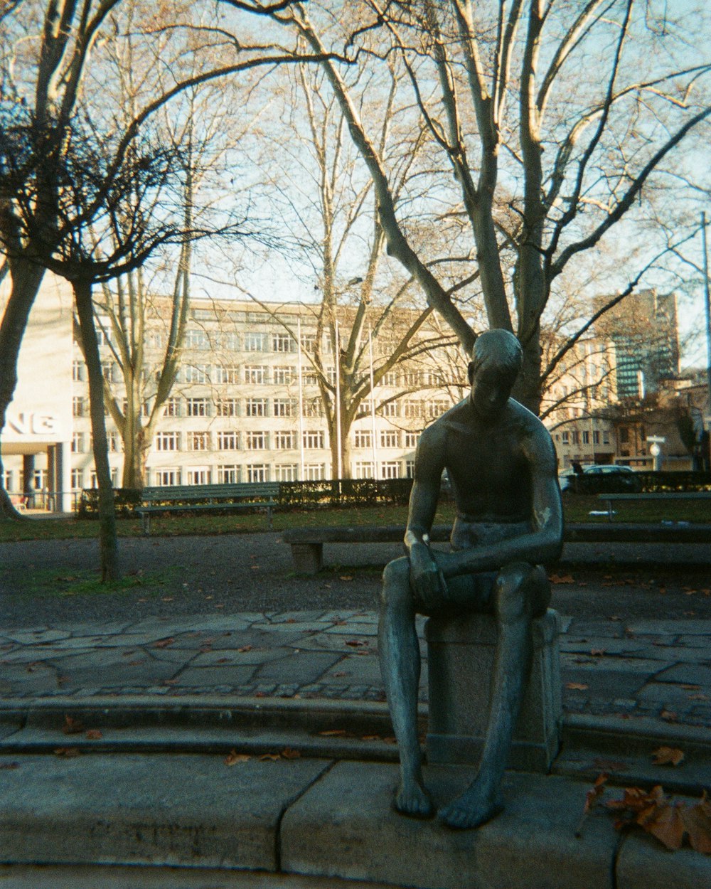 a statue of a man sitting on a park bench