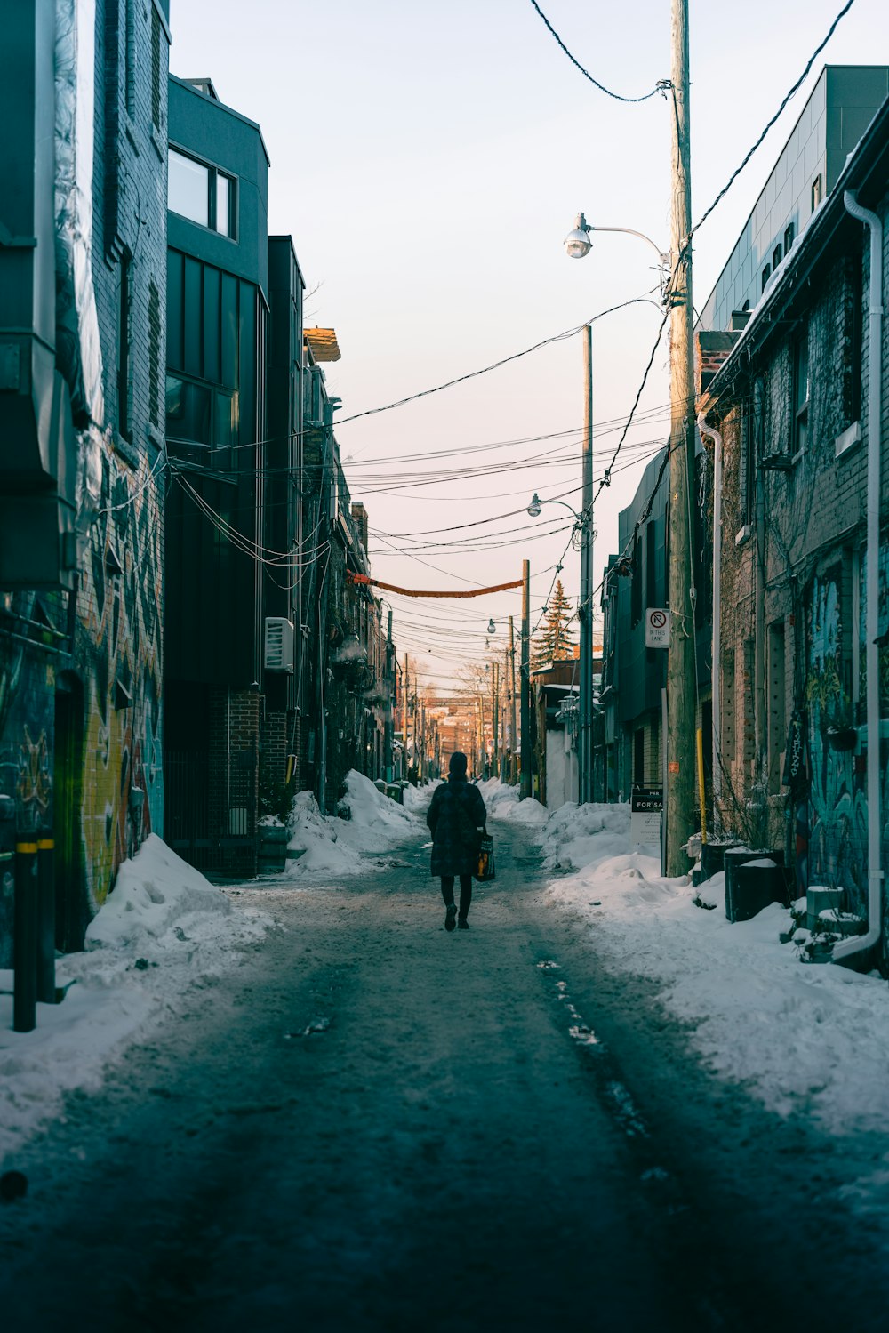 a person walking down a snowy street next to tall buildings
