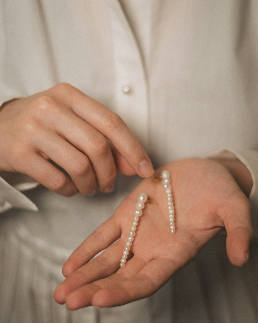 a person wearing a white shirt holding a pair of pearls