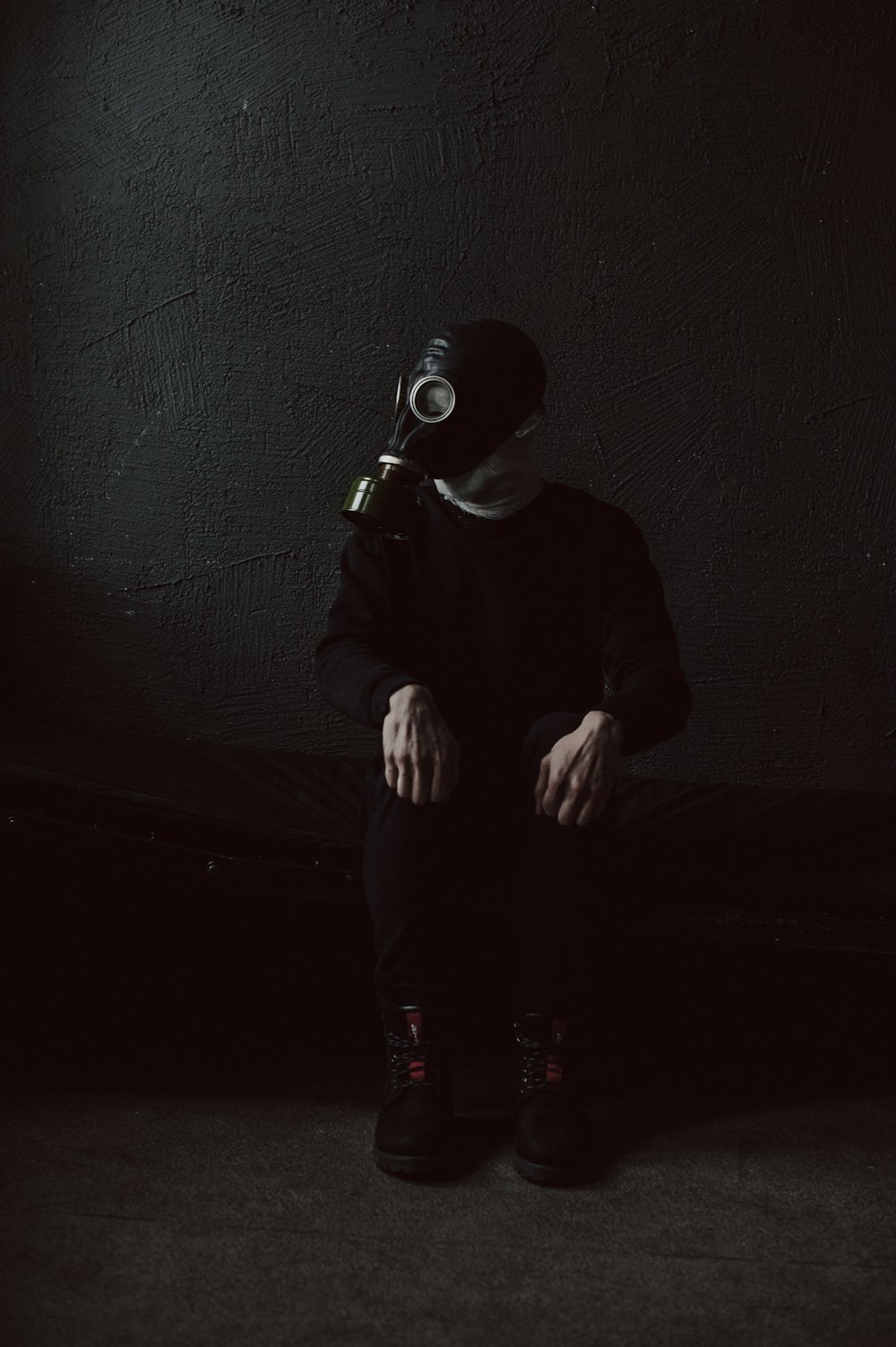 a man in a gas mask sitting on a bed