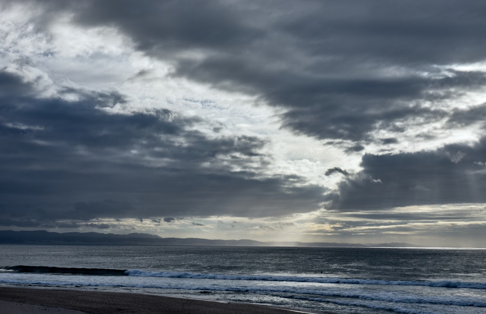 a cloudy sky over the ocean and a beach