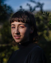 a woman with a black shirt and a tree in the background