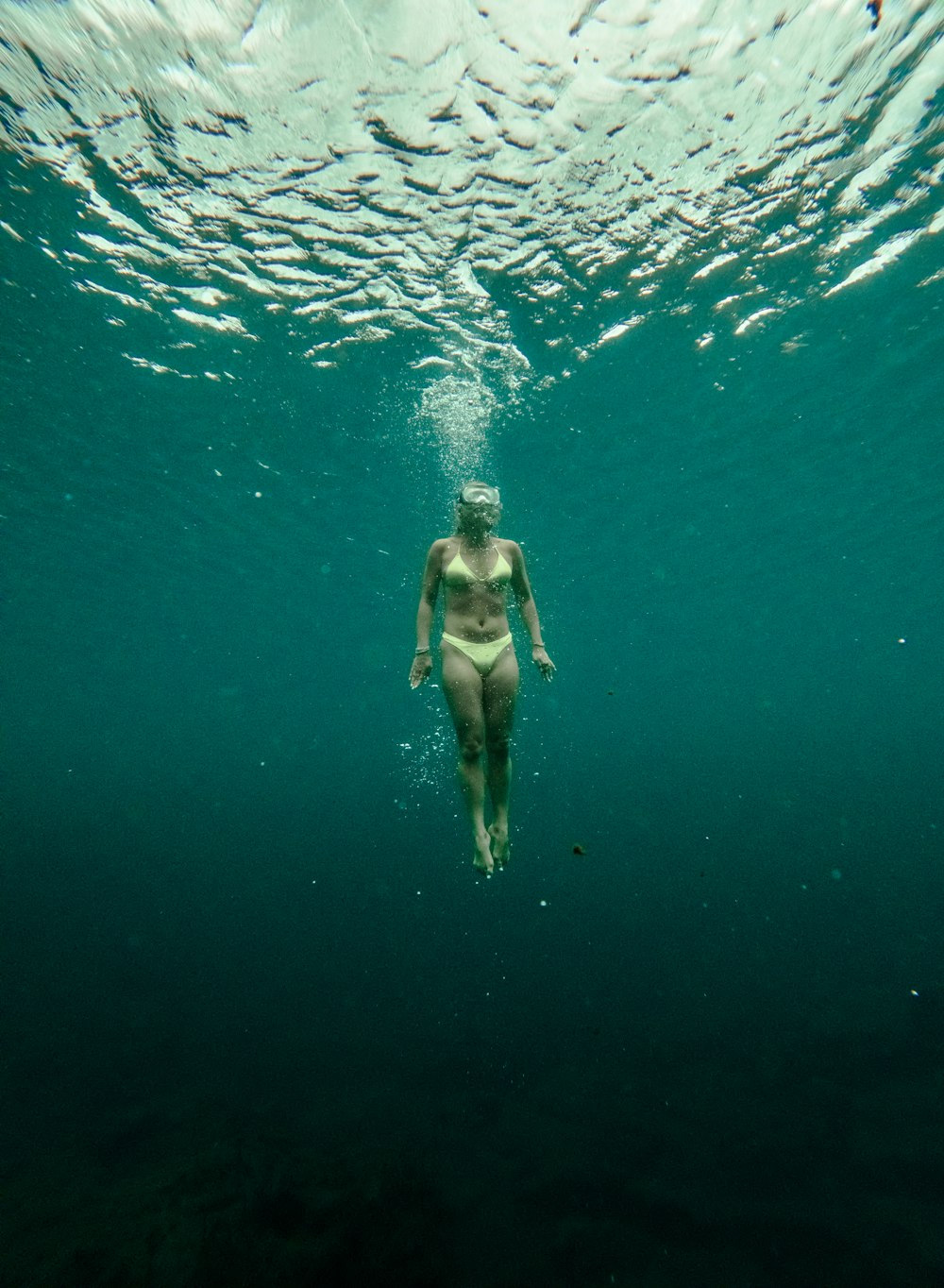 a woman in a bikini swims under the water