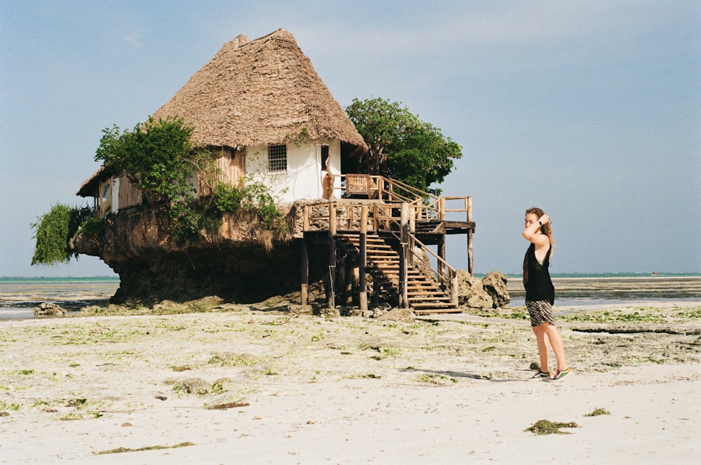 a woman standing on a beach next to a house