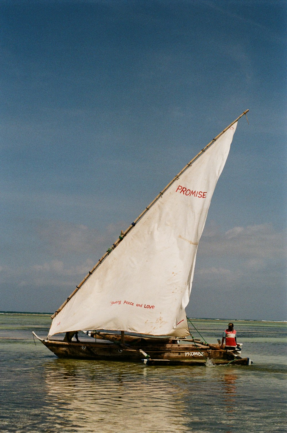 un velero con una vela blanca en un cuerpo de agua