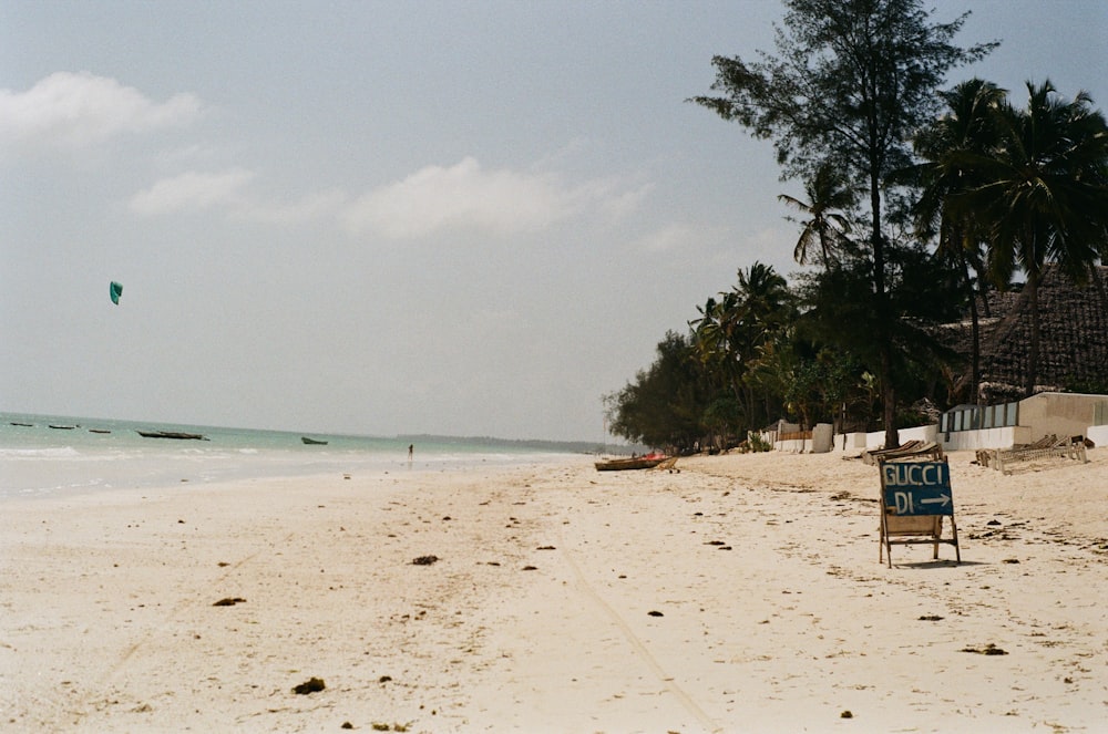 a beach with a sign and a kite flying in the sky