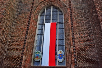 a tall brick building with a red white and blue flag hanging from it's