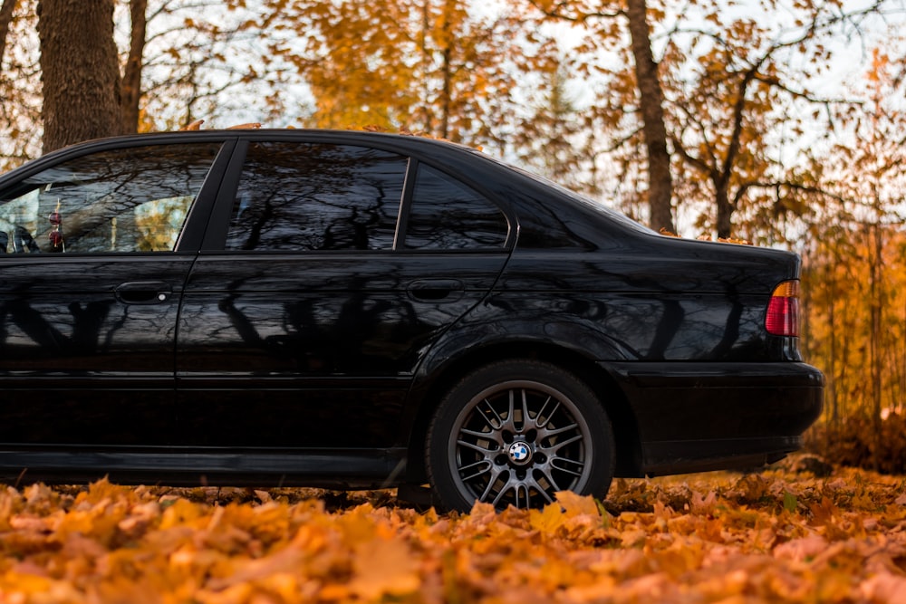 a black car is parked in the leaves