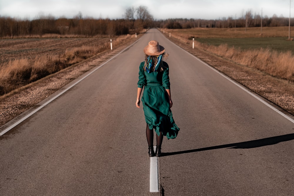 a woman in a green dress is walking down the road