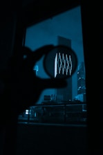 A silhouette of a detective holding a magnifying glass against a backdrop of city lights at night.