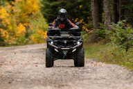 a man riding an atv down a dirt road