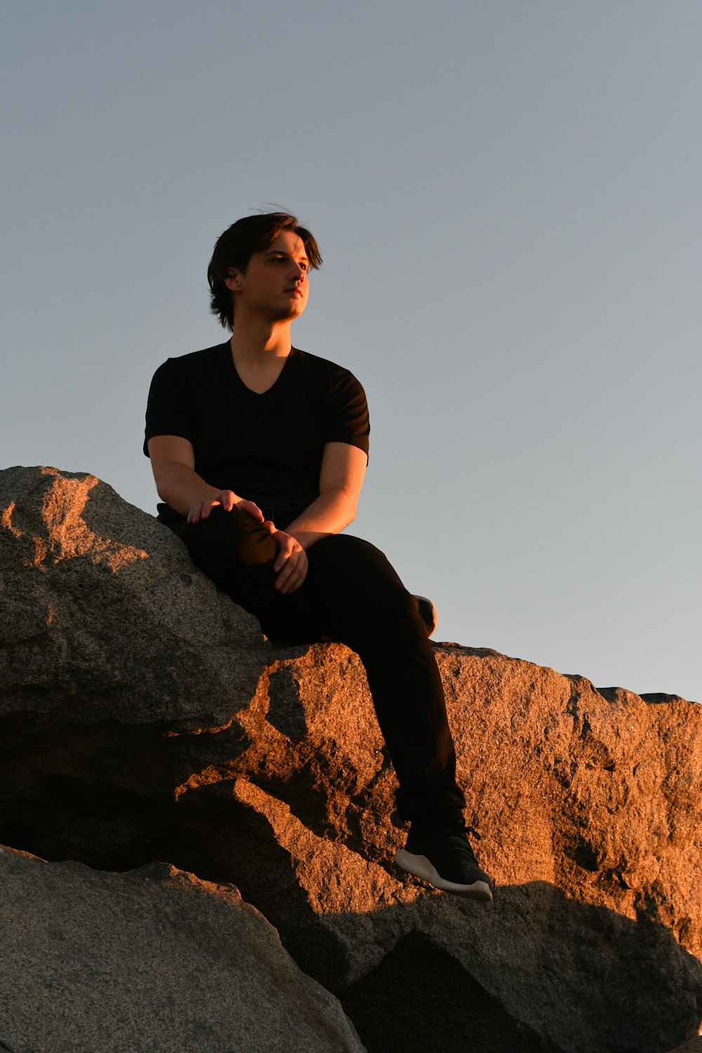 a man sitting on top of a large rock