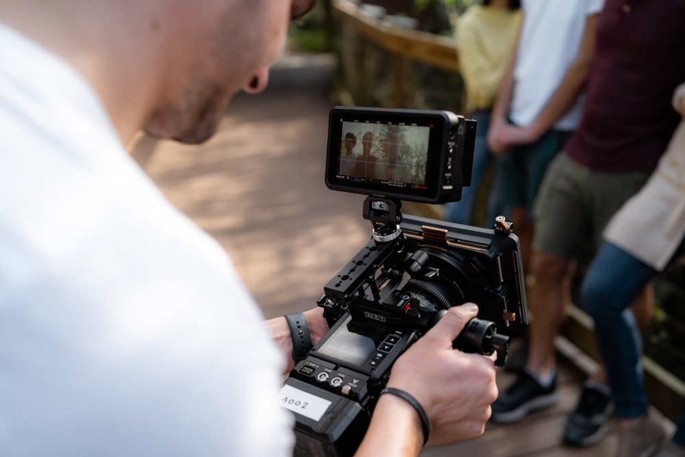 Un uomo che tiene una macchina fotografica di fronte a un gruppo di persone