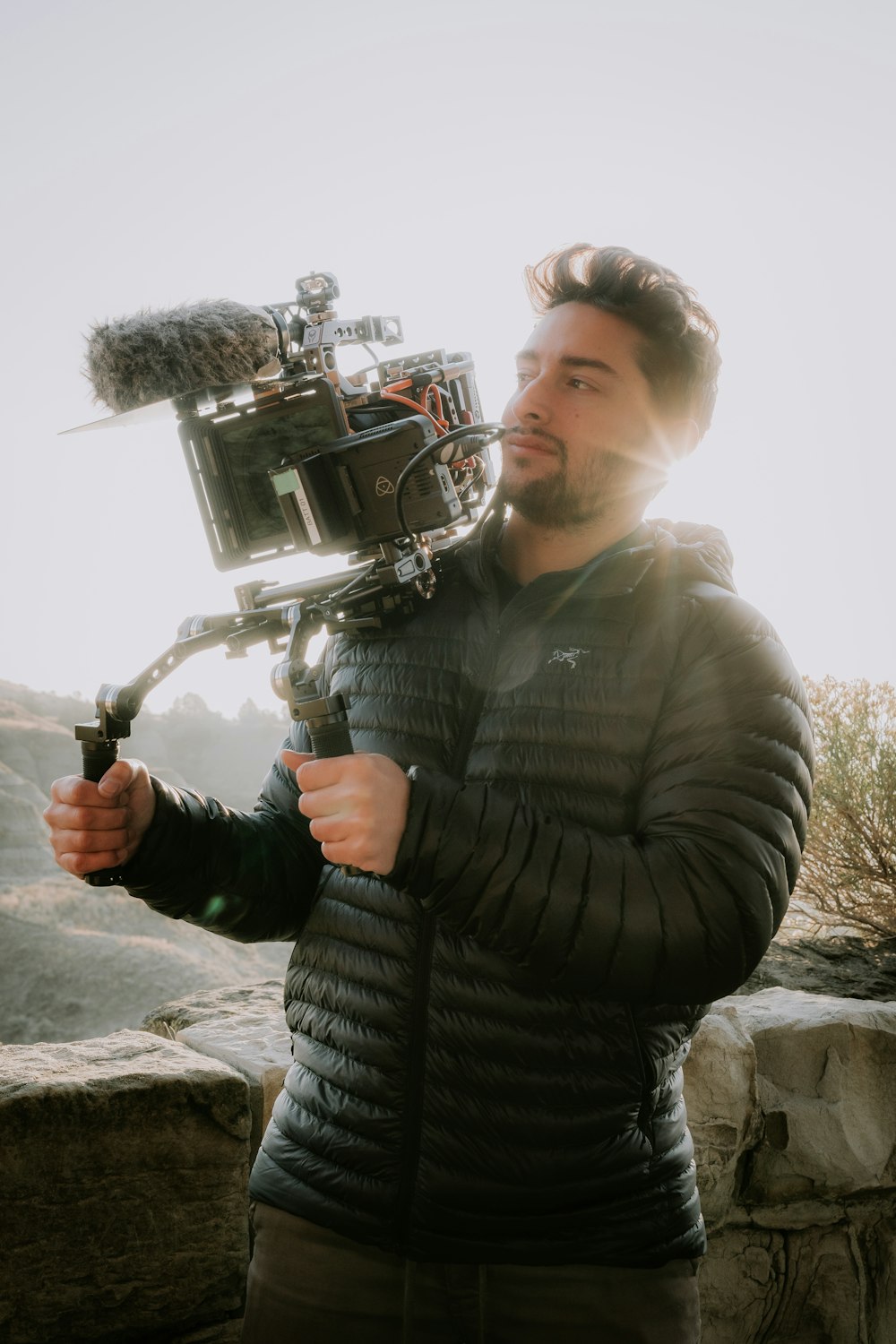 a man holding a camera on top of a mountain