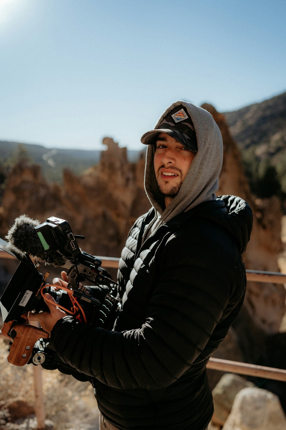 Un uomo che tiene una macchina fotografica davanti a una montagna