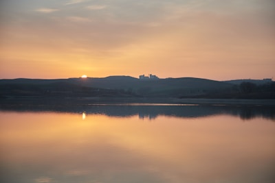 Delicate watercolor landscape capturing a serene sunset over hills.