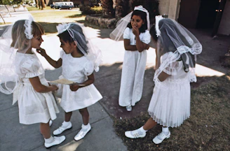 a group of young girls dressed in white standing next to each other
