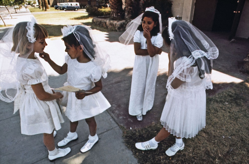 a group of young girls dressed in white standing next to each other