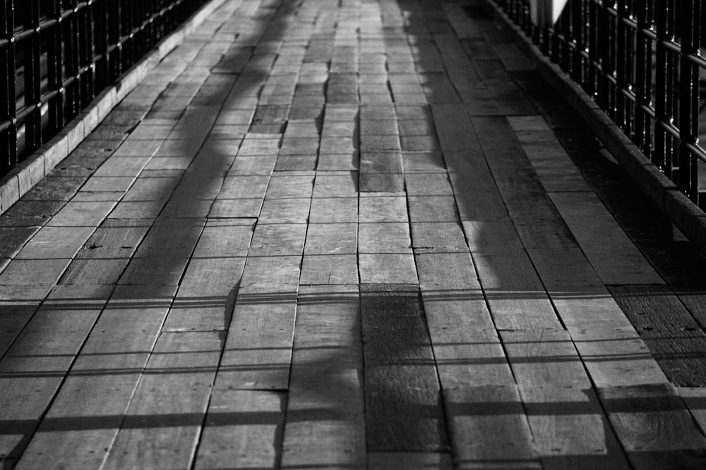 a black and white photo of a person walking across a bridge