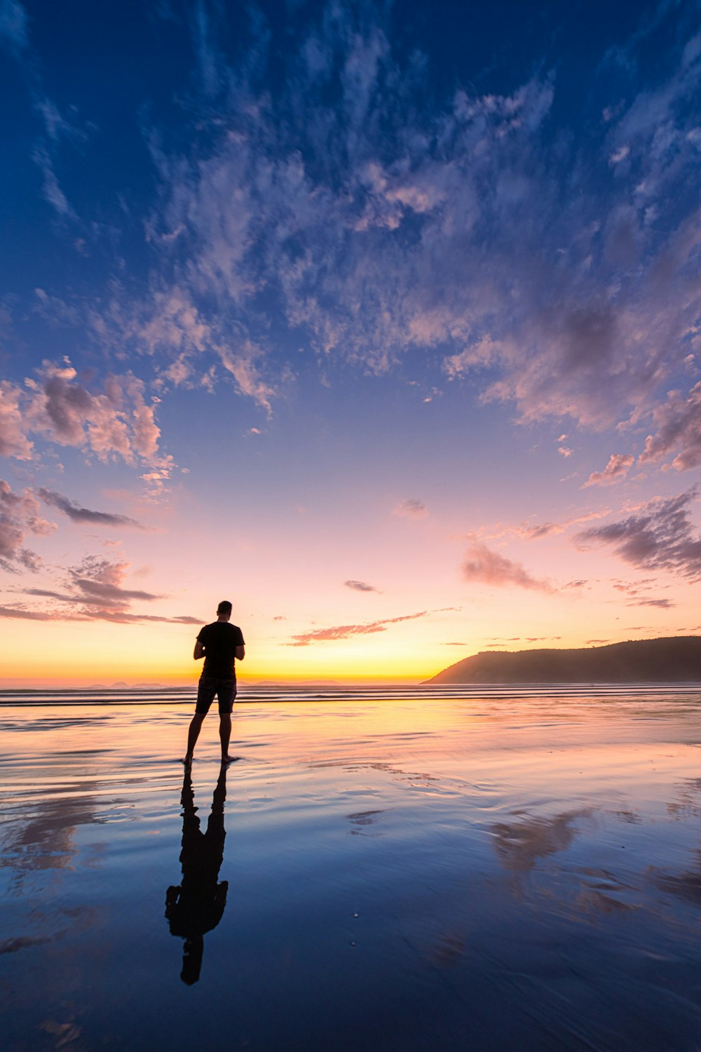 a person standing in the water at sunset