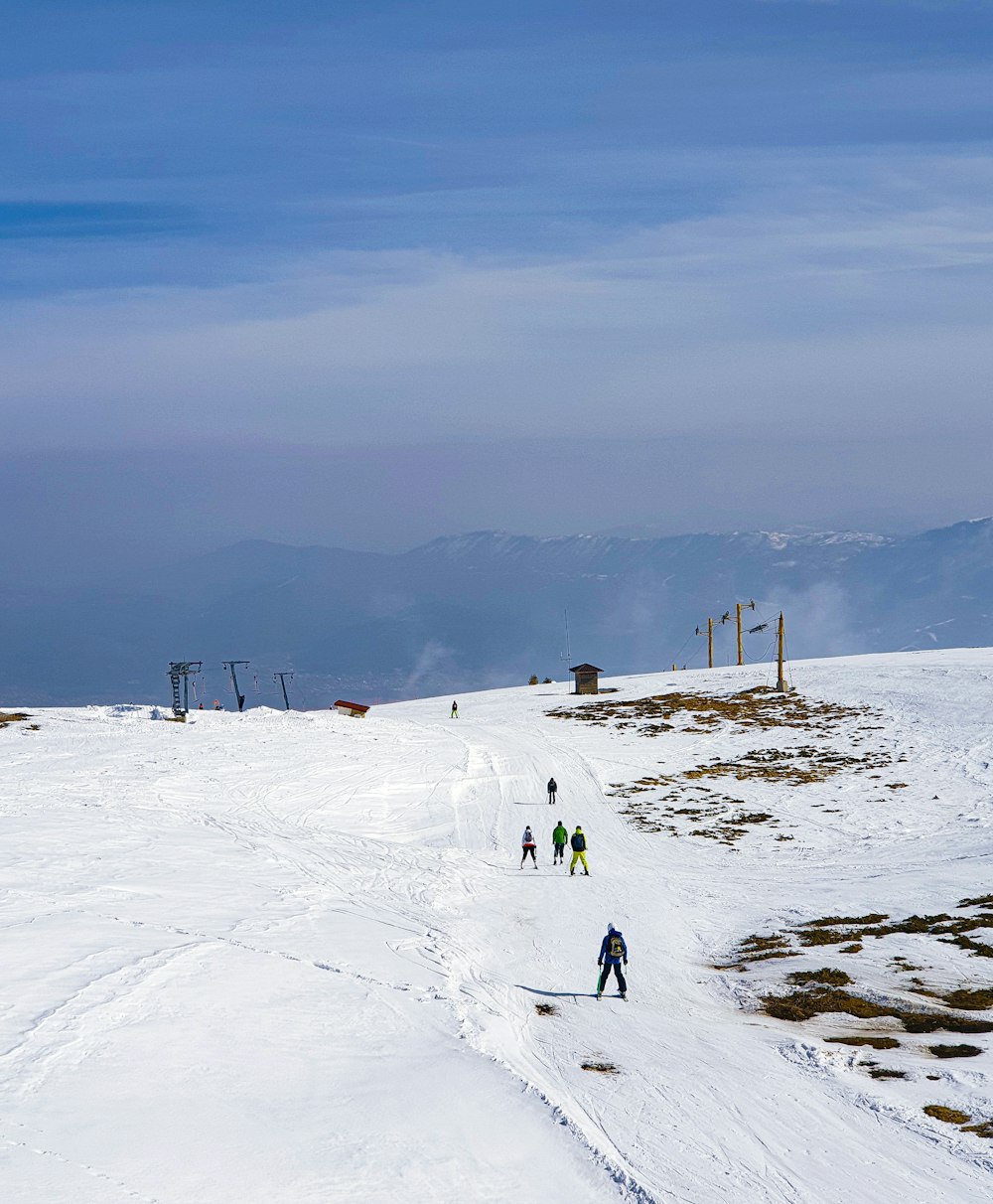 a group of people riding skis down a snow covered slope