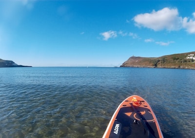 Close-up of a paddleboarding adventure on calm, transparent waters with green hills in the background
