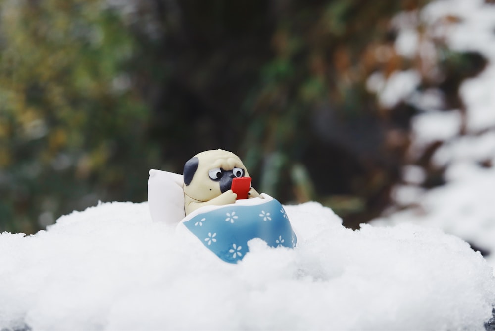 Un petit oiseau jouet assis sur un tas de neige