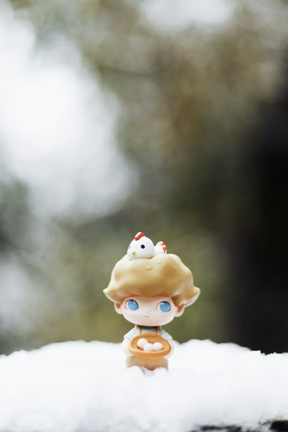 a little doll sitting on top of a pile of snow