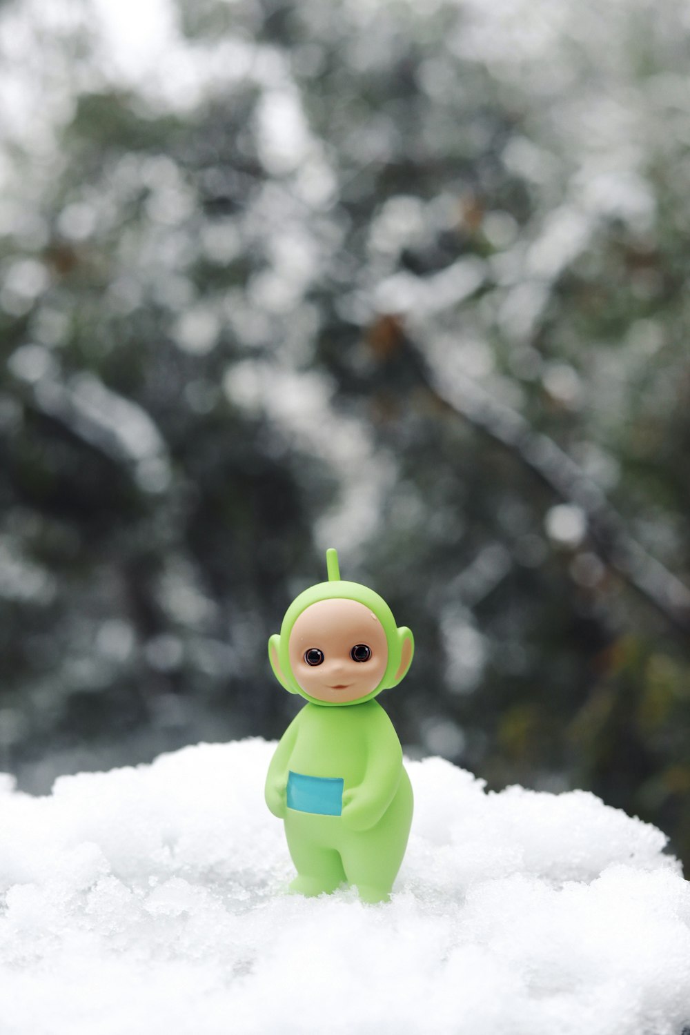 Un pequeño juguete sentado sobre el suelo cubierto de nieve