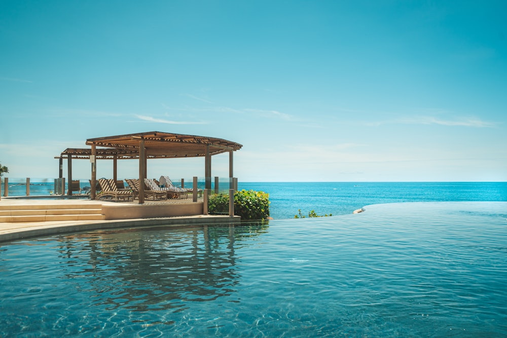 a gazebo next to a swimming pool with a view of the ocean