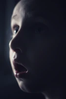 A close-up of a child’s amazed face while watching a balloon artist crafting animal shapes.