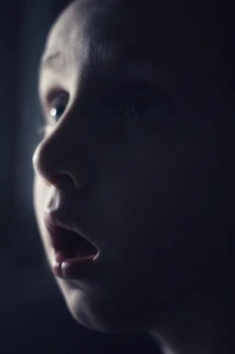 A close-up of a child’s amazed face while watching a balloon artist crafting animal shapes.