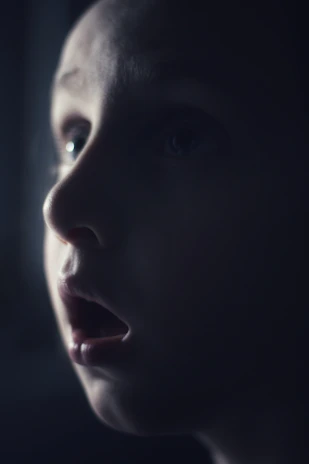A close-up of a child’s face lit up with excitement while listening to a story.