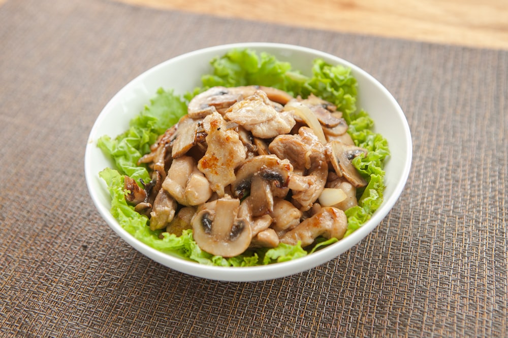 a white bowl filled with lettuce and mushrooms