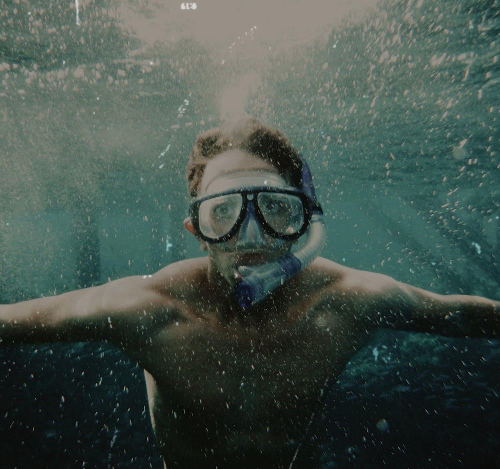 a man wearing goggles under water in a pool