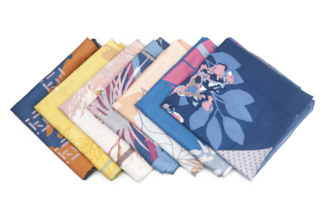A flat lay of folded sarees with different textures and patterns, showcasing the premium fabric quality.