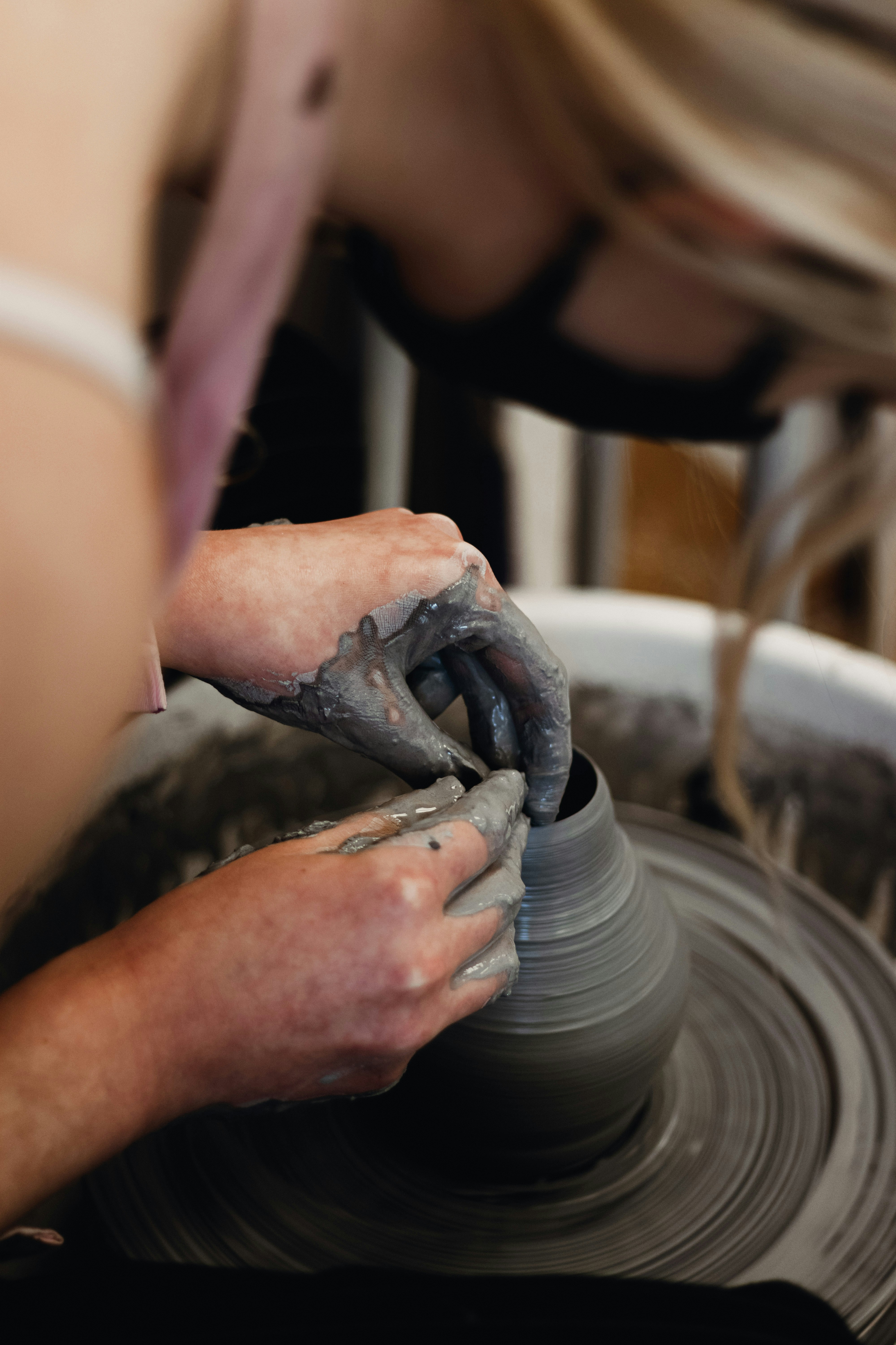 a woman is making a vase on a potter's wheel