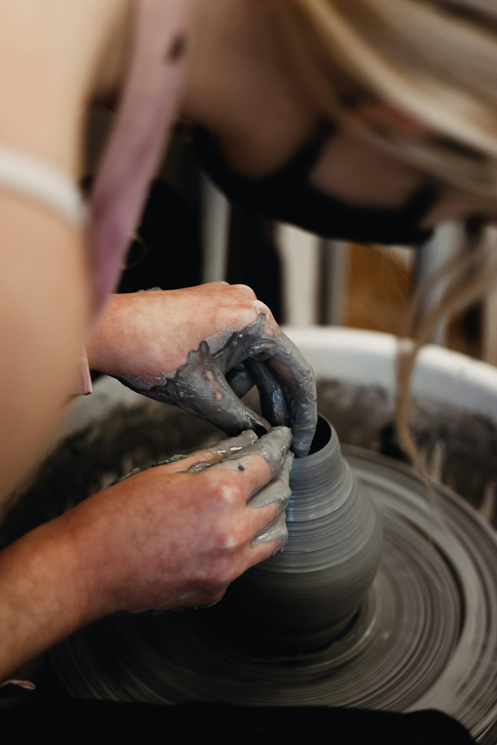 a woman is making a vase on a potter's wheel