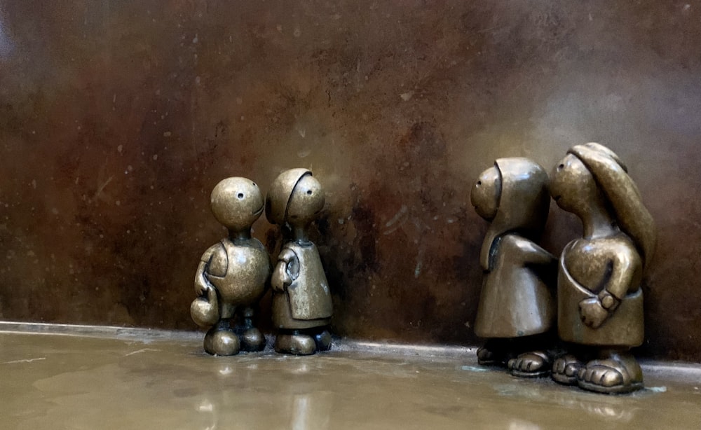 three metal figurines of people standing next to each other